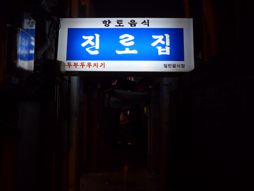 看板が煌々と輝く、真っ暗な路地…