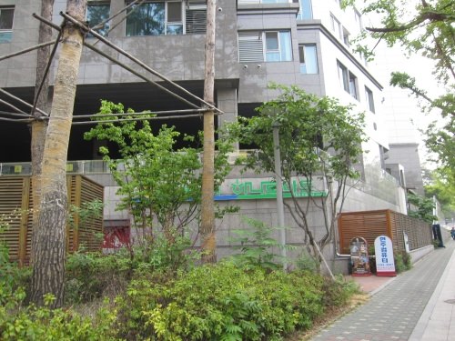 植木の向こうにハナロマートのロゴが見えます。