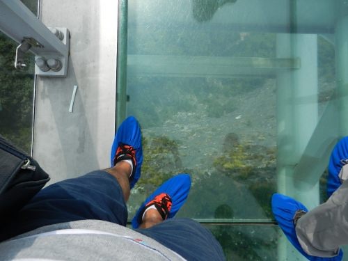 スカイウォーク　　透明の床から足元が透けて見える。靴のブルーのカバーは靴に付いた汚れで床が汚れないように着けるのだと思う。